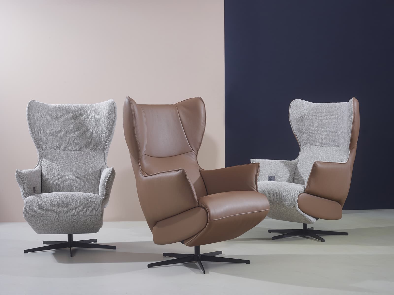 Set van drie design relaxfauteuils in stof en leercombinatie op een lichte vloer